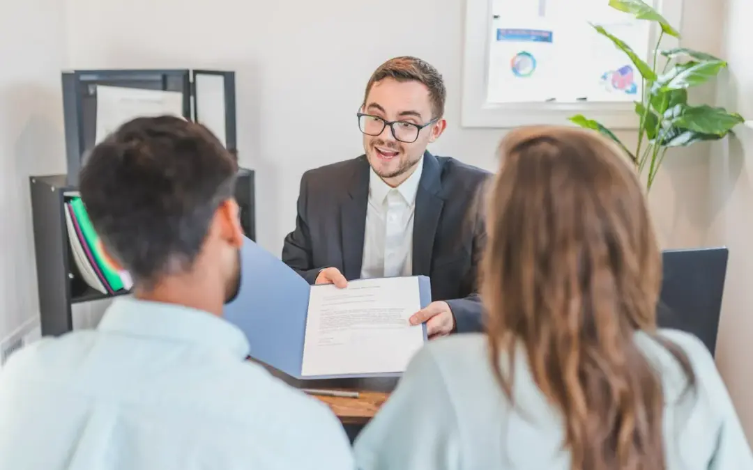 Mortgage broker showing a remortgage contract to a couple during an advice consultation.