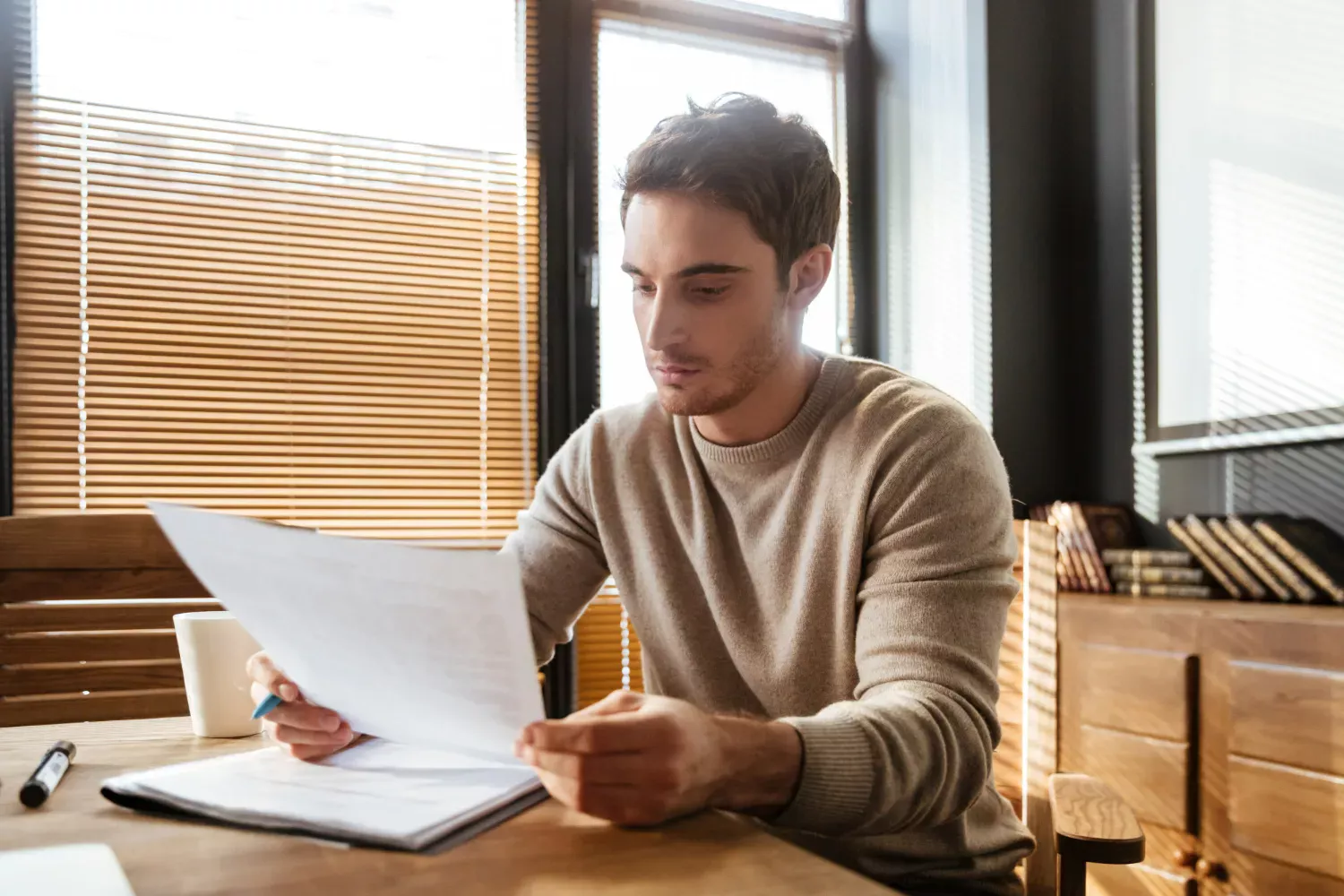 A man carefully reading remortgage application documents at a desk.