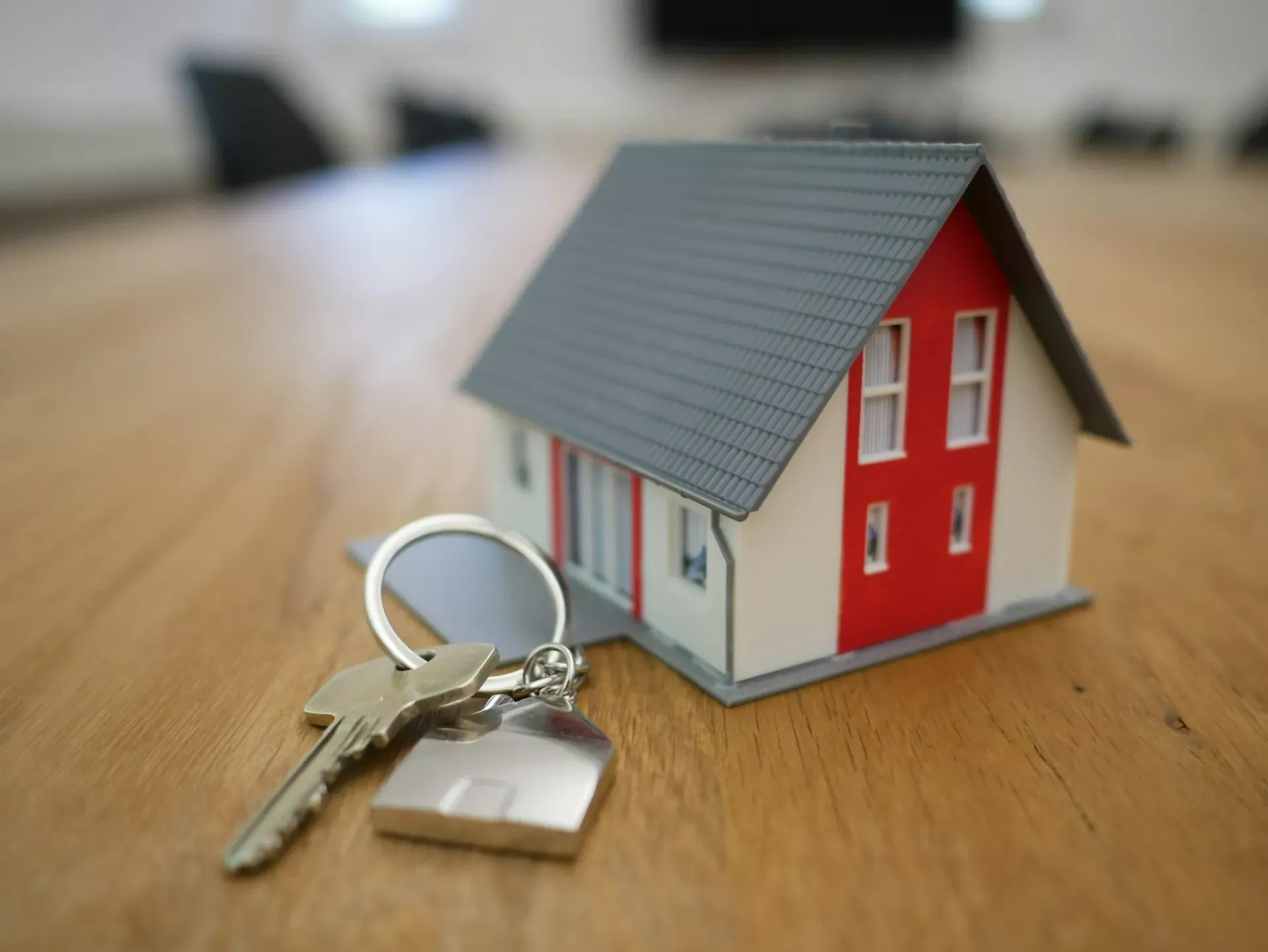Miniature house model and property keys on a table representing remortgage planning and timing.
