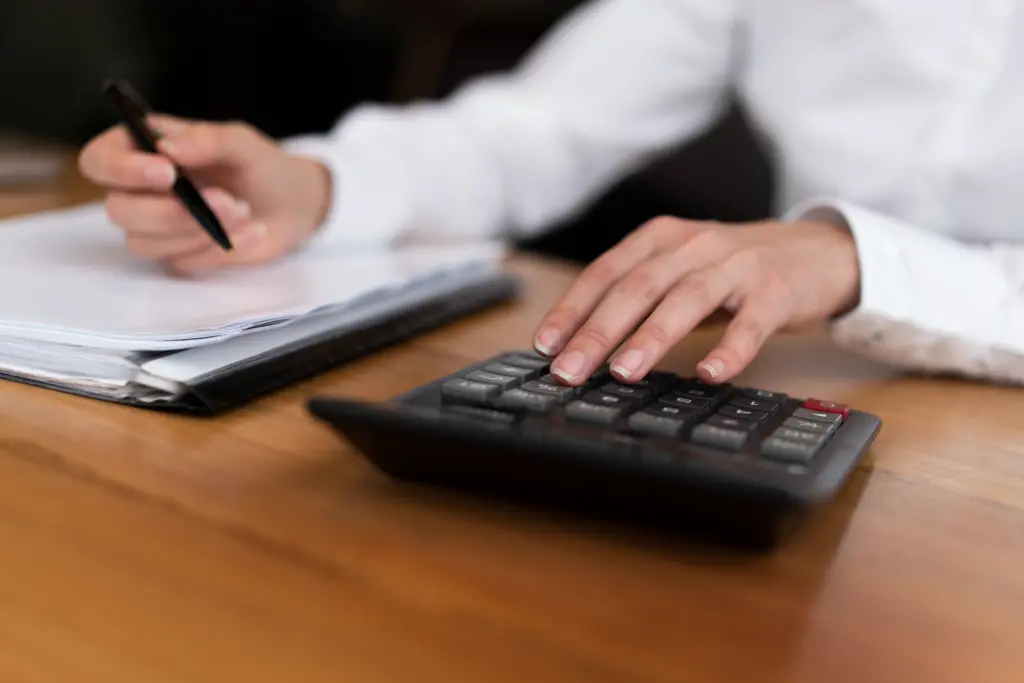Person using a calculator to review remortgage fees and paperwork.