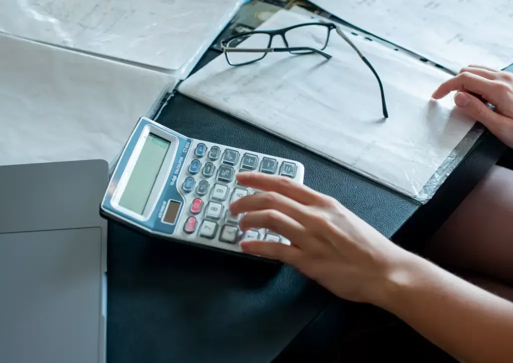 Person using a calculator while reviewing financial records.